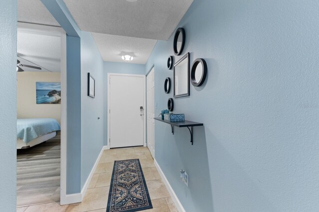 entryway with light tile patterned floors, baseboards, and a textured ceiling