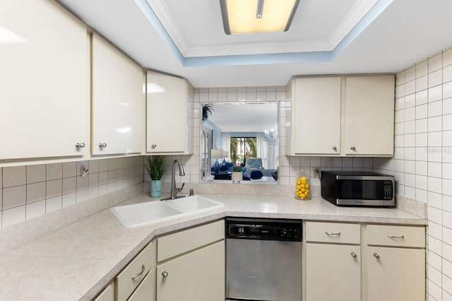 kitchen featuring a tray ceiling, stainless steel appliances, light countertops, ornamental molding, and a sink