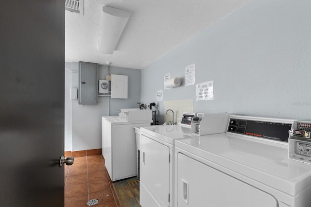 common laundry area with dark tile patterned flooring, independent washer and dryer, electric panel, and baseboards