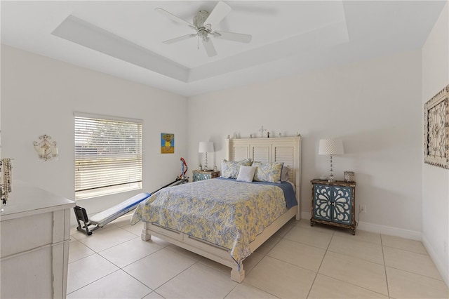 bedroom with ceiling fan, a tray ceiling, and light tile floors