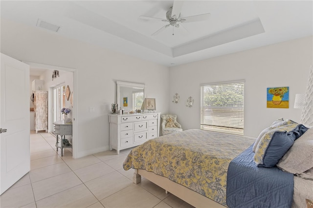 bedroom featuring a raised ceiling, ceiling fan, and light tile floors