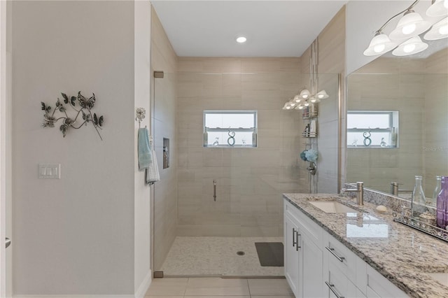 bathroom with a shower with door, tile flooring, and vanity