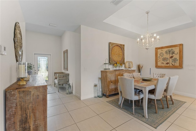 tiled dining area with a raised ceiling and a notable chandelier