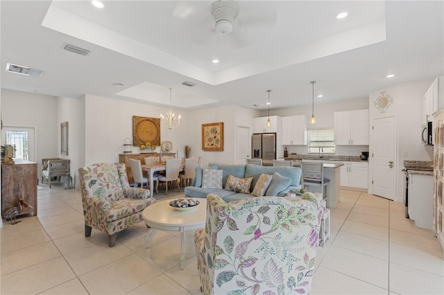 living room with sink, ceiling fan with notable chandelier, a raised ceiling, and light tile patterned flooring