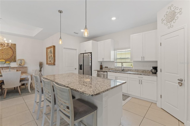 kitchen with pendant lighting, light tile floors, a center island, white cabinets, and appliances with stainless steel finishes