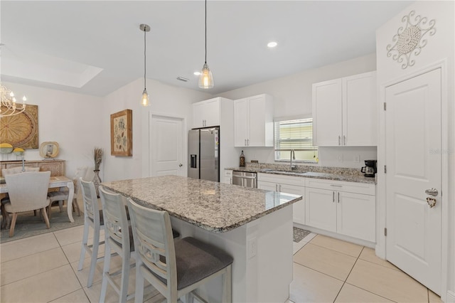 kitchen with white cabinetry, hanging light fixtures, light stone counters, and stainless steel appliances