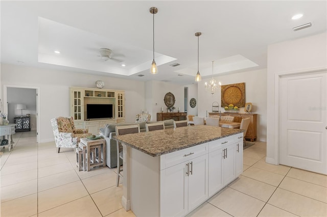 kitchen featuring a tray ceiling, a kitchen island, and white cabinets