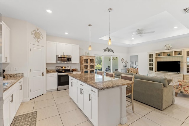 kitchen with appliances with stainless steel finishes, white cabinetry, and a raised ceiling