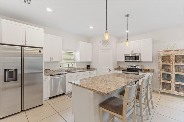 kitchen with stainless steel appliances, a kitchen island, hanging light fixtures, sink, and white cabinetry