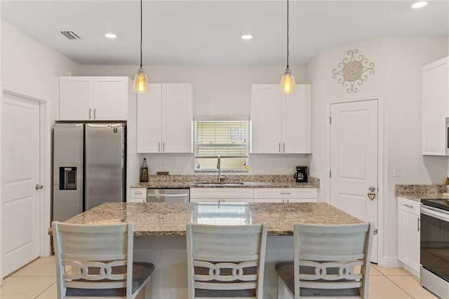 kitchen with a kitchen island, appliances with stainless steel finishes, sink, white cabinets, and light stone counters