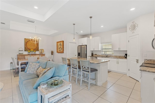 kitchen with stainless steel fridge with ice dispenser, hanging light fixtures, white cabinetry, and a center island