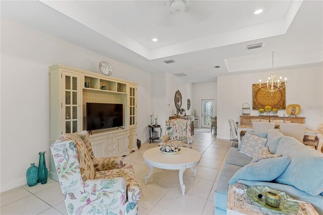 living room featuring a tray ceiling, light tile floors, and a chandelier