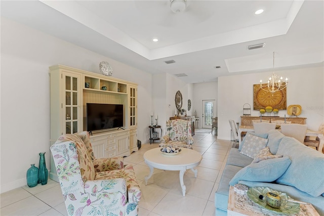 tiled living room featuring a notable chandelier and a tray ceiling