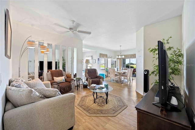 living room with ceiling fan with notable chandelier and light hardwood / wood-style floors