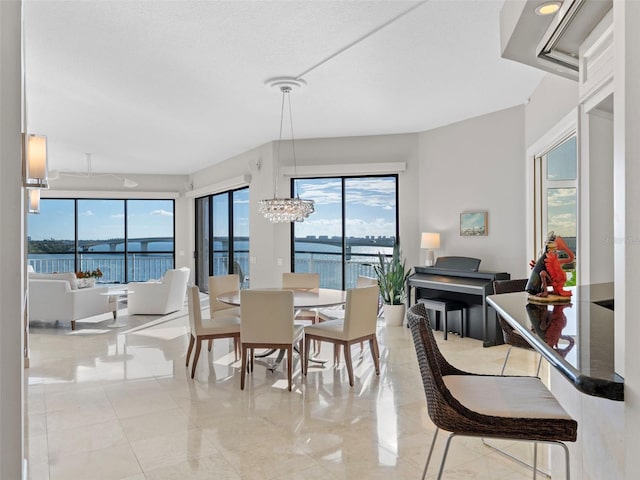 dining space featuring a chandelier, a textured ceiling, and a water view