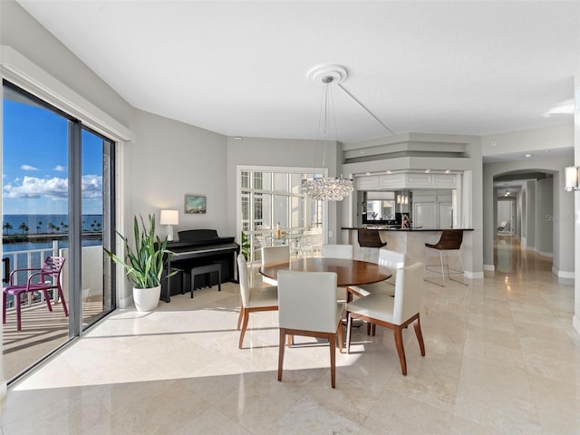 dining room with a water view, an inviting chandelier, and plenty of natural light