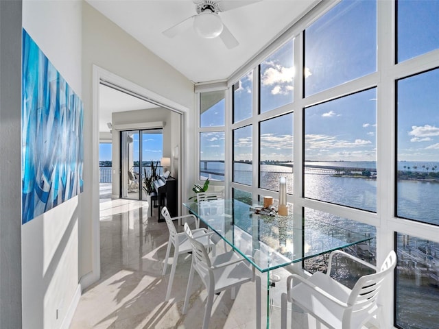 sunroom with ceiling fan and a water view