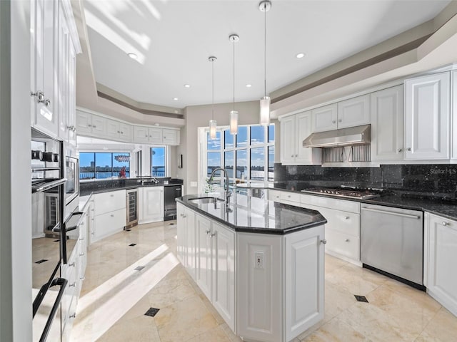 kitchen featuring a kitchen island with sink, white cabinets, sink, stainless steel appliances, and beverage cooler