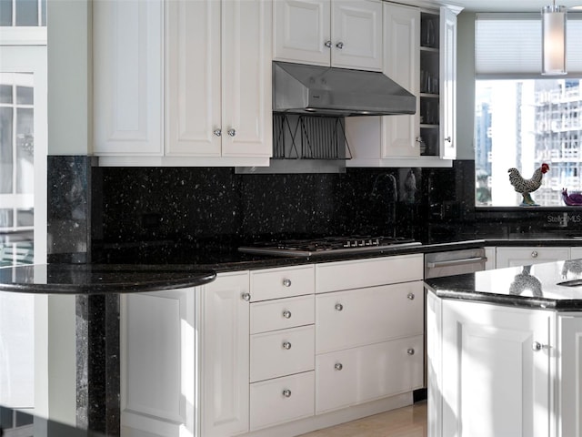 kitchen with ventilation hood, white cabinetry, stainless steel gas cooktop, and dark stone countertops