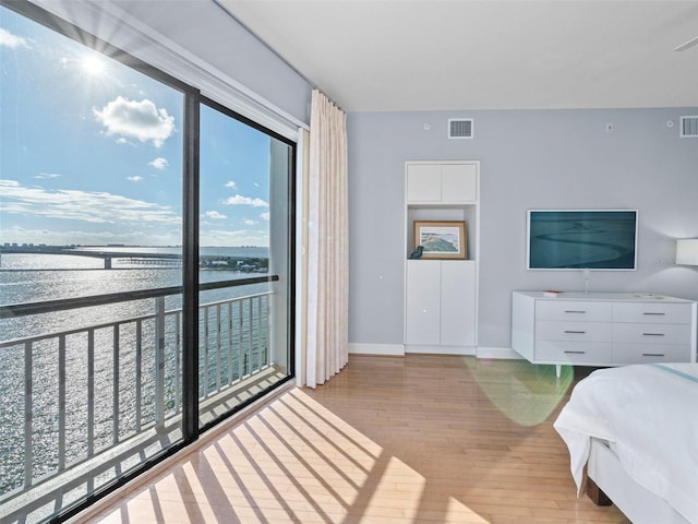 bedroom with a water view and light hardwood / wood-style floors