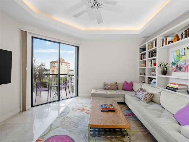 living room with ceiling fan and a tray ceiling