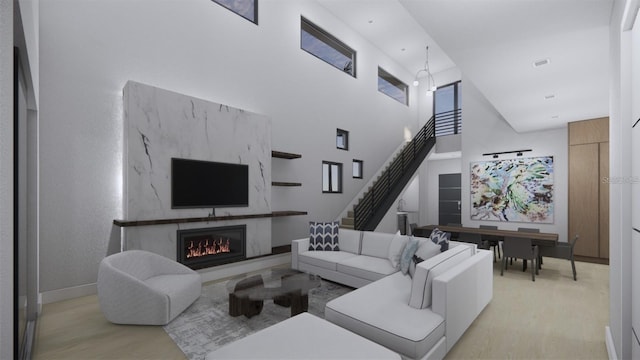 living room featuring a premium fireplace, a towering ceiling, and light hardwood / wood-style flooring