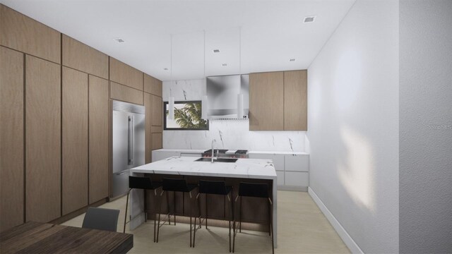 kitchen featuring light stone counters, a breakfast bar area, a center island, wall chimney exhaust hood, and sink