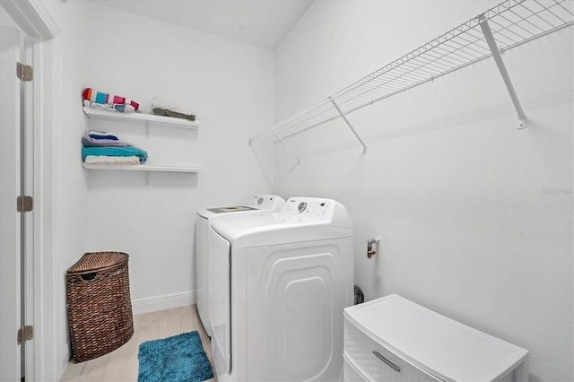 clothes washing area with independent washer and dryer and light hardwood / wood-style flooring