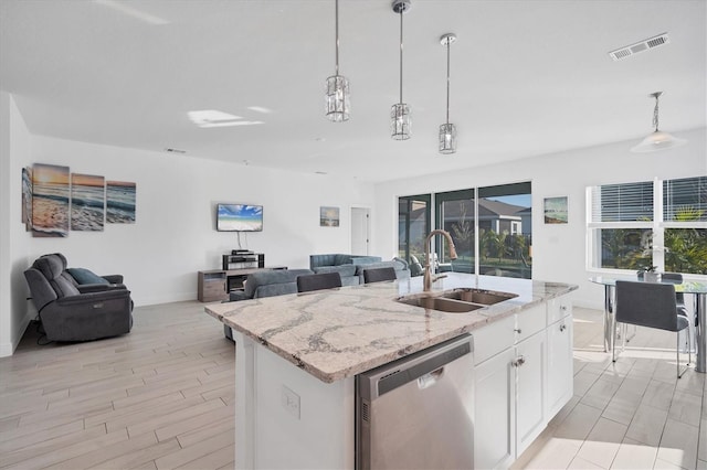 kitchen featuring an island with sink, white cabinetry, stainless steel dishwasher, and sink