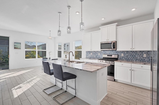 kitchen with white cabinetry, pendant lighting, a kitchen island with sink, and appliances with stainless steel finishes