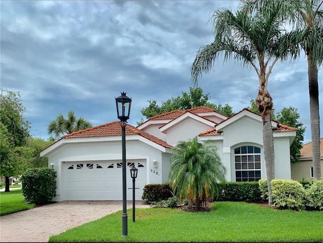 mediterranean / spanish house with a garage and a front lawn