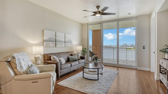 living room featuring a textured ceiling, ceiling fan, a healthy amount of sunlight, and floor to ceiling windows