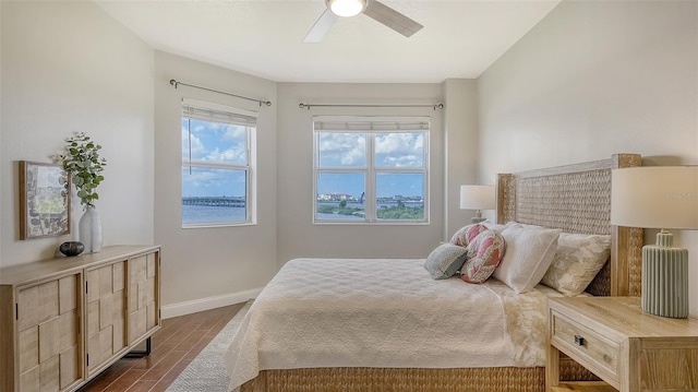 bedroom featuring multiple windows, dark hardwood / wood-style floors, and ceiling fan