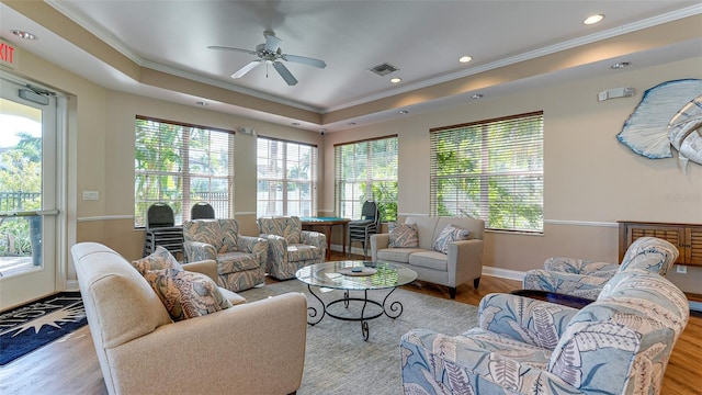 living room featuring light wood-type flooring, a tray ceiling, and a wealth of natural light