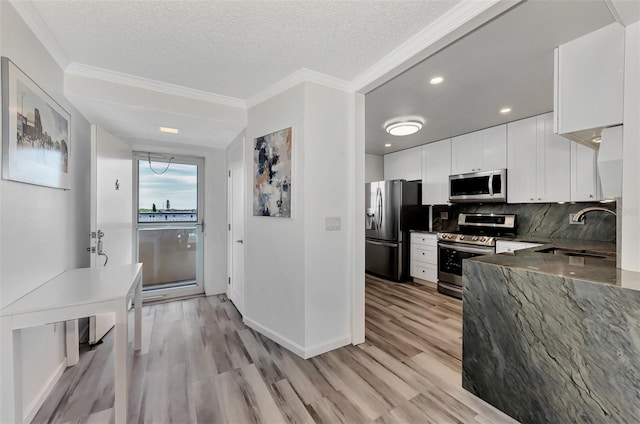 kitchen featuring stainless steel appliances, sink, a textured ceiling, white cabinetry, and tasteful backsplash