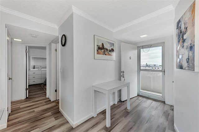 entryway featuring a textured ceiling, light wood-type flooring, and crown molding