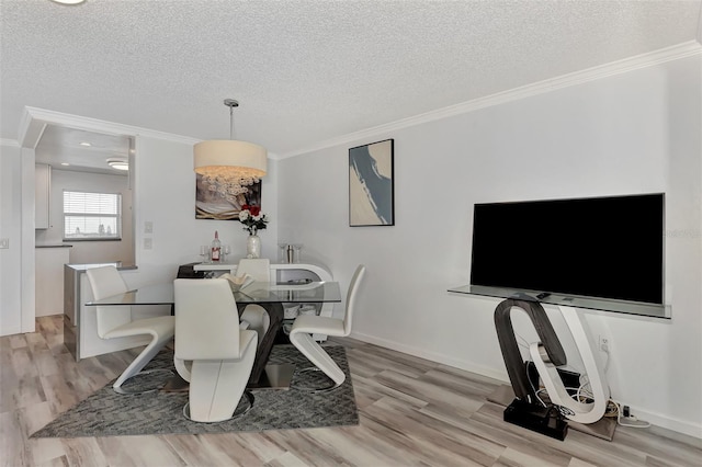 dining space featuring light hardwood / wood-style floors, crown molding, and a textured ceiling