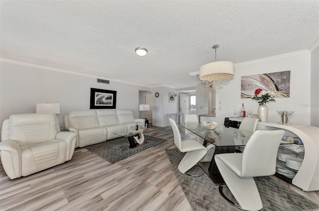 dining space featuring a textured ceiling, light wood-type flooring, and crown molding