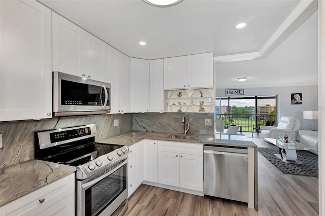 kitchen featuring sink, white cabinets, light stone counters, and appliances with stainless steel finishes