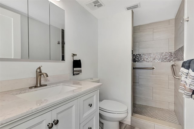 bathroom featuring toilet, vanity, and tiled shower