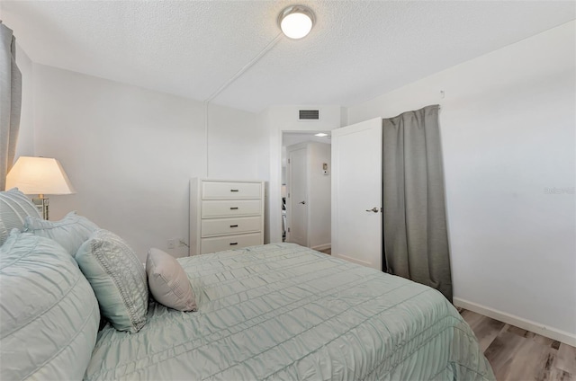 bedroom with a textured ceiling and light wood-type flooring