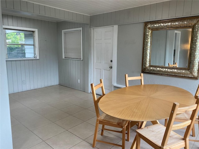 dining room with wood walls and light tile patterned floors