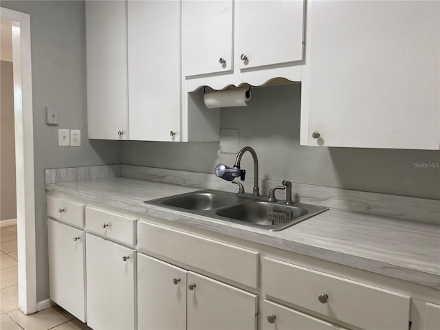 kitchen with white cabinets, sink, and light tile patterned floors