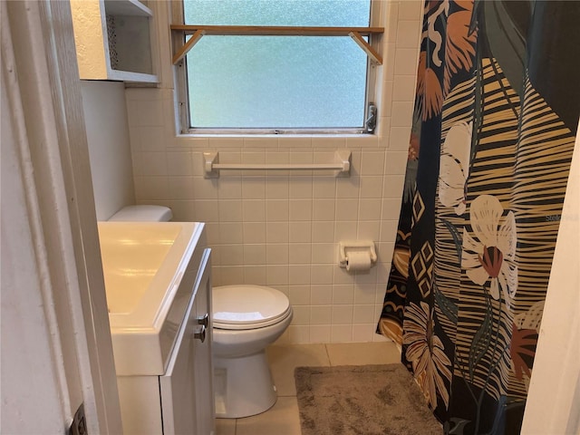 bathroom with tile walls, vanity, tile patterned floors, and toilet