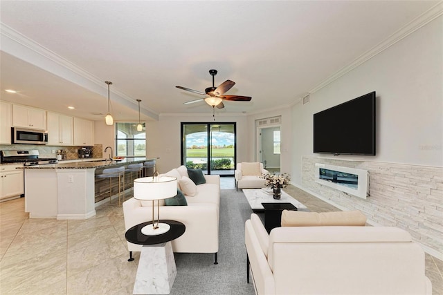 living room featuring ceiling fan, light tile patterned floors, sink, and crown molding