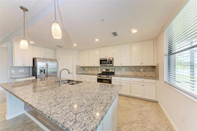 kitchen with decorative light fixtures, sink, white cabinetry, appliances with stainless steel finishes, and an island with sink