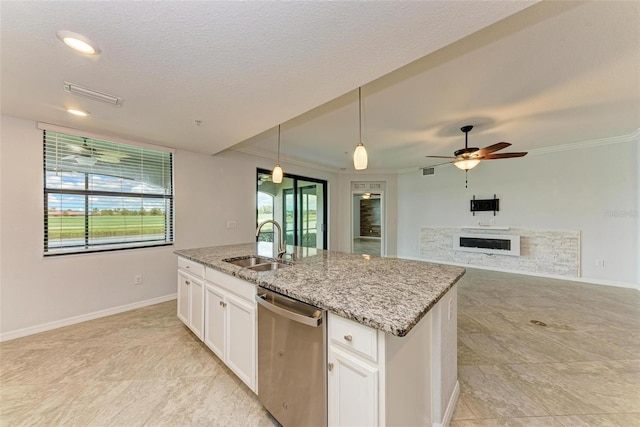 kitchen with light stone countertops, white cabinets, an island with sink, sink, and stainless steel dishwasher