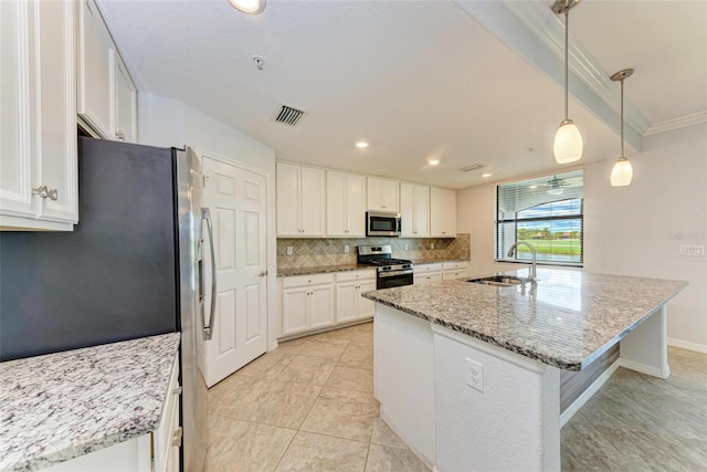 kitchen featuring pendant lighting, white cabinets, stainless steel appliances, sink, and a kitchen island with sink