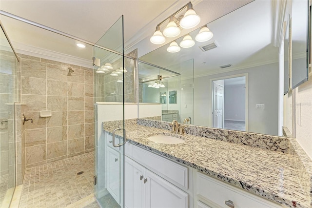 bathroom with ceiling fan, vanity, ornamental molding, and a tile shower