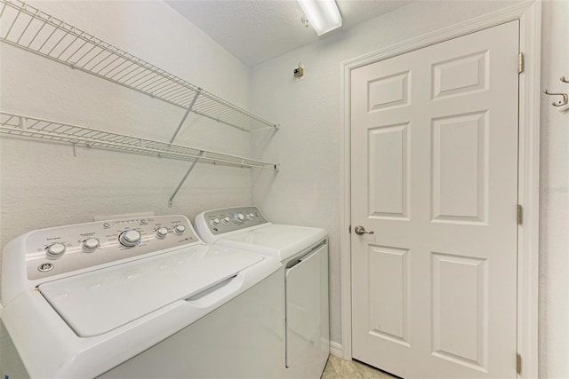 laundry room with a textured ceiling and washing machine and dryer